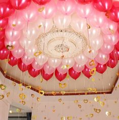 balloons and confetti are hanging from the ceiling in a room with white walls