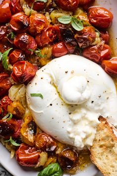 an image of a plate of food with tomatoes and bread on the side that is ready to be eaten