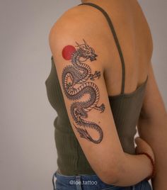 a woman with a dragon tattoo on her arm, holding a red ball in her hand