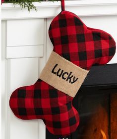 a red and black stocking with the word lucky on it hanging from a fireplace