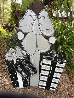 some black and white paper cut outs are on the ground in front of trees with flowers