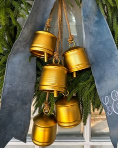 four golden bells hanging from a christmas wreath