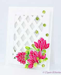 a white card with pink flowers and green leaves on the front, next to a crochet background