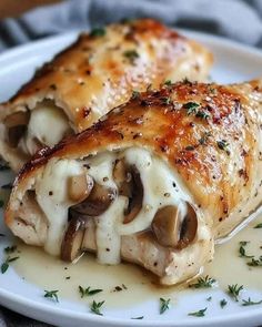 two pieces of chicken covered in cheese and mushrooms