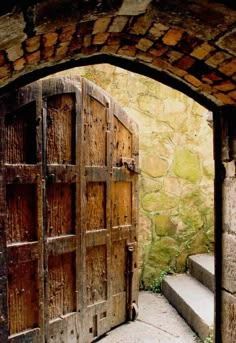 an open wooden door in front of a stone wall with steps leading up to it