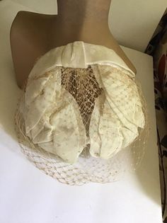 "Vintagw 1950's 1960's Off White hat with veiling. Has an Off White Velvet bow in the back. *MORE INFORMATION BELOW* CONDITION: I note a hole in the veiling on the left side (SEE PIX). Also a split in the veiling on the right side (SEE PIX). Sold As Is! MEASURES: Left to right UP and OVER the hat~12\" Front to back~7\" *WE APOLOGIZE~BUT WE NO LONGER SHIP TO GERMANY, ITALY OR SPAIN. IF ORDERS COME IN FROM GERMANY, ITALY OR SPAIN, WE WILL HAVE TO CANCEL THEM AND REFUND YOUR MONEY. SORRY FOR THIS I Vintage Cream Fascinator For Evening, Vintage Cream Headpiece For Evening, Vintage White Fascinator For Evening, Vintage White Evening Fascinator, Vintage White Headpieces For Evening, Vintage Cream Fascinator For Royal Ascot, Cream Vintage Fascinator For Royal Ascot, Vintage Cream Headpieces For Vintage Events, Vintage Fitted Cream Fascinator