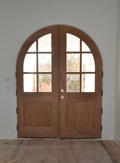 an empty room with two wooden doors and hard wood flooring in front of it