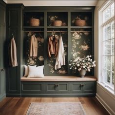 a room filled with lots of green cupboards and coats hanging on the wall next to a window