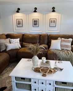 a living room filled with furniture and pillows on top of a white table next to a brown couch