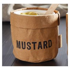 there is a cup with mustard in it on the table next to a box that says mustard