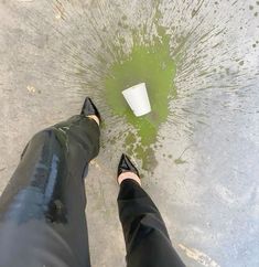 a person standing in front of a puddle with their feet on the ground next to a paper cup