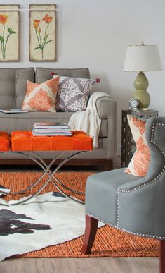 an orange and gray living room with pictures on the wall, couches and lamps