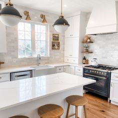 a kitchen with white cabinets and wooden stools next to an oven in the center