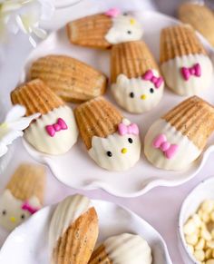 hello kitty cookies on plates with flowers and marshmallows next to them for dessert