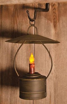 an old fashioned lantern hanging on a wooden wall with a candle in the center,