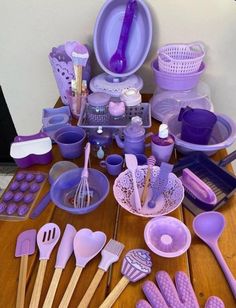 a table topped with lots of purple utensils and other kitchen accessories on top of a wooden table