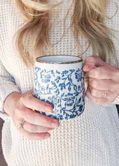 a woman holding a blue and white coffee cup