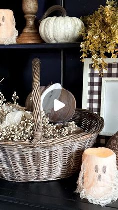 a wicker basket filled with pumpkins and other decorative items sitting on a shelf