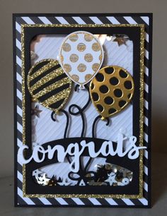 congratulations card with gold foil balloons and black and white stripes on the bottom, in front of a gray background