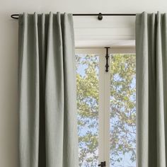 an open window with green curtains in front of it