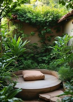 an outdoor seating area in the middle of some plants and trees with a pillow on it