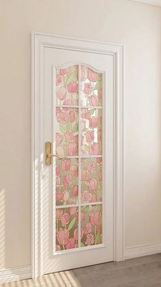 an open door with pink flowers painted on the glass and gold hardware, in front of a white wall