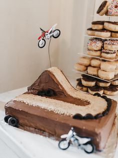 a cake shaped like a dirt bike on top of a table next to doughnuts