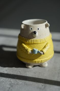 a ceramic bear with a yellow sweater on