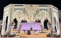 a stage set up for a wedding with flowers and decorations on the stage, surrounded by chairs