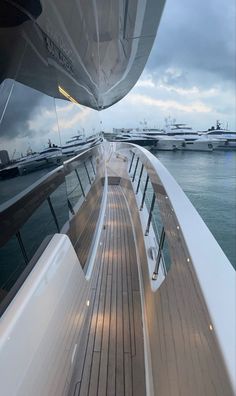 the back end of a boat in the water with many other boats behind it and cloudy skies