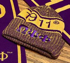 two purple and yellow hats are laying next to each other on a wooden surface,