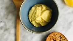 a blue bowl filled with food next to a piece of bread on top of a white counter