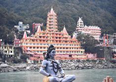 a person sitting in the middle of a body of water with buildings behind them and trees on both sides