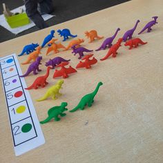 a group of toy dinosaurs sitting on top of a wooden table next to a marker