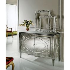 an ornate silver cabinet with mirrors and flowers in the corner, against a white wall