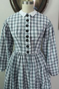 An 1860's style handmade one piece, front buttoning cotton day dress. The bodice is flatlined with white sheeting cotton, seams are pinked or selvage is left intact. The bodice is shaped with darts, the back has false piped seams. The skirt is unlined. This is a style from an era meant to be worn with a corset, petticoats, crinoline etc. to achieve the correct silhouette. The dress is front buttoning, with a dog leg closure. The buttons are black antique Czech glass, with brass shanks. It fits a 1860s Day Dress, Cotton One Piece, Dog Leg, Working Class, Day Dress, Historical Fashion, Dress Clothes For Women, Petticoat, Czech Glass