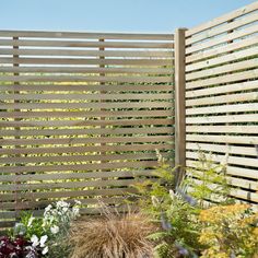 a wooden fence surrounded by plants and flowers