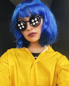 a woman with blue hair and black polka dots on her eyes wearing yellow raincoat