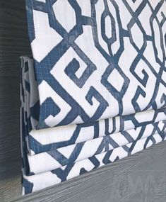 a blue and white patterned curtain hanging on the side of a wooden window sill