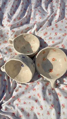 three white bowls sitting on top of a bed