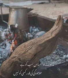 a piece of wood sitting on top of a fire pit next to a metal pot