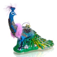 a glass ornament with a peacock on it's back and feathers hanging from the top