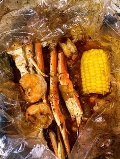 crab legs and corn on the cob wrapped in plastic