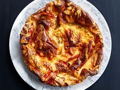 a white plate topped with a pizza covered in cheese and toppings on top of a black table