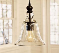 a glass bell light hanging from a ceiling in a room with white walls and windows