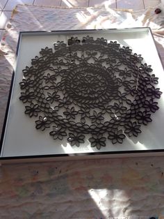 an art piece is displayed on a table with white paper and black flowers in the center