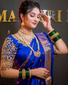 a woman in a blue sari with gold jewelry on her neck and hands behind her head