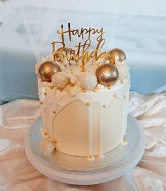 a white cake with gold decorations and happy birthday written on top