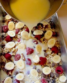 a bowl filled with granola, fruit and yogurt next to a glass of orange juice