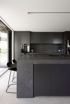 a modern kitchen with an island counter and black chairs